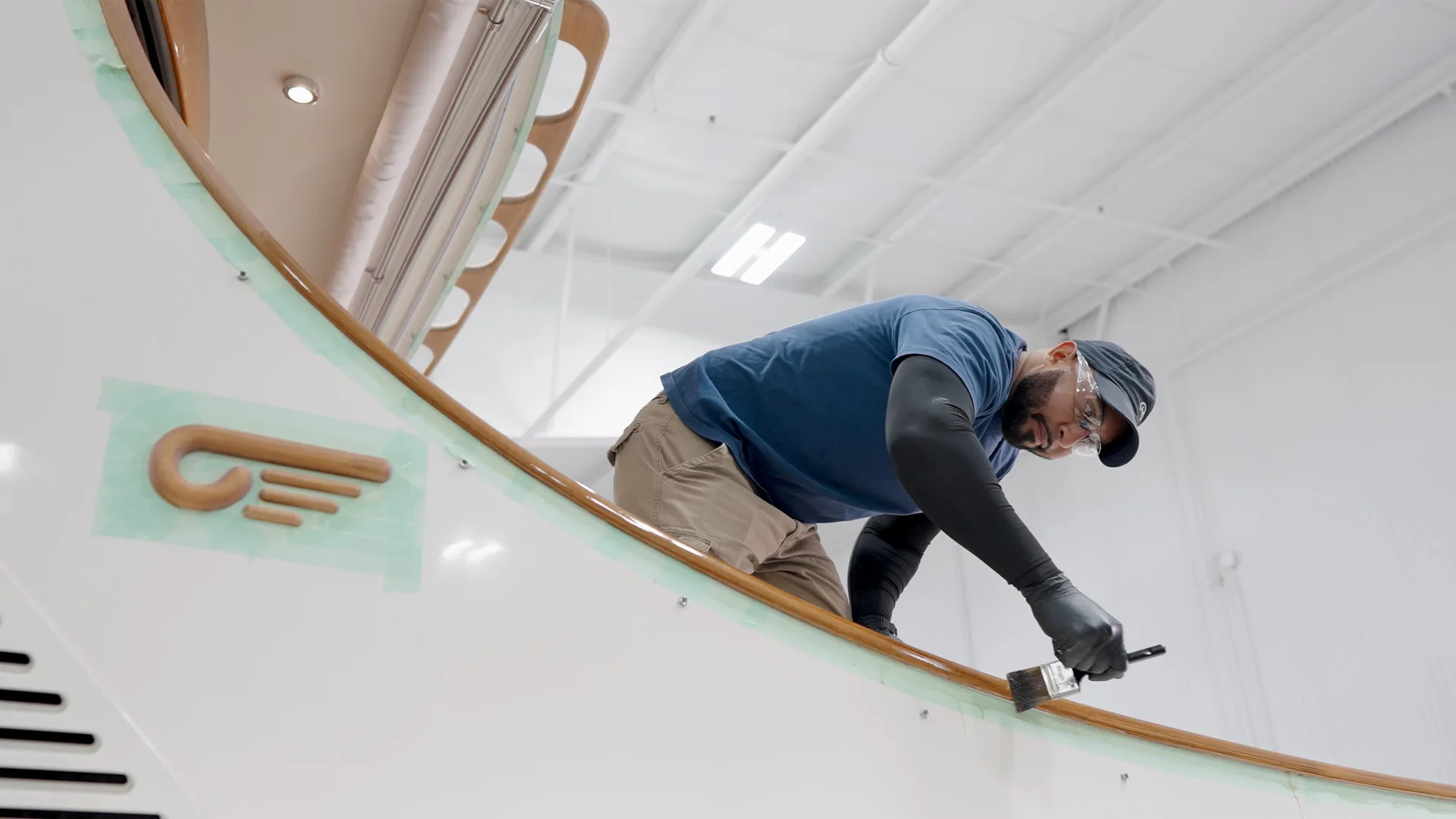 Technician sanding the side of a white yacht hull in Portsmouth