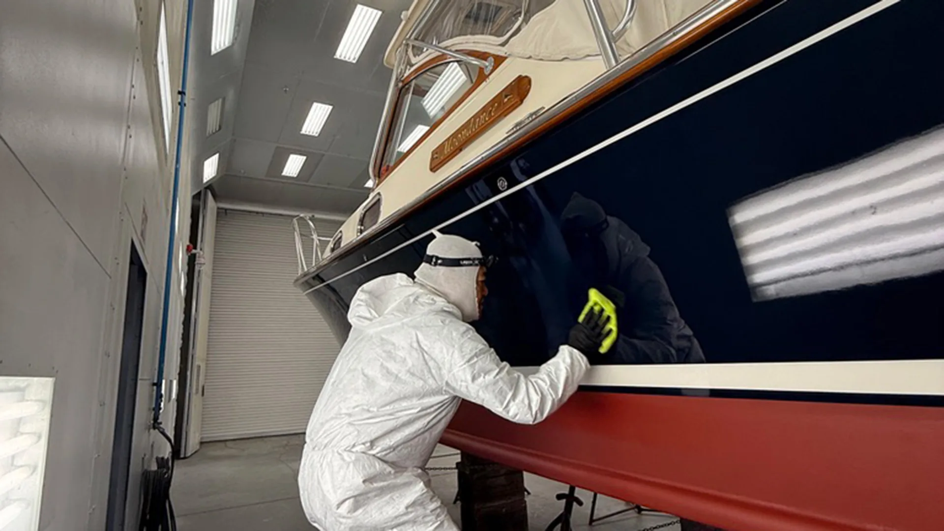 Technician detailing a white hull inside the Stamford service bay
