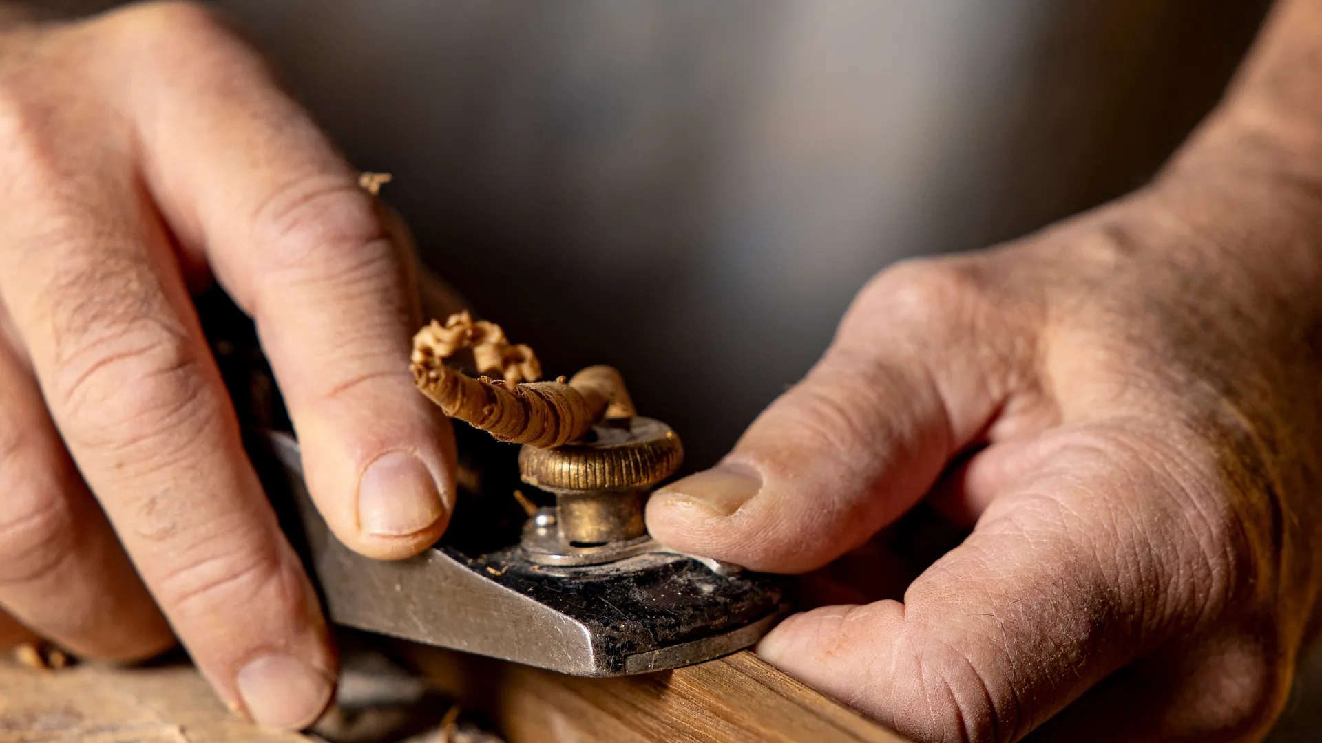 Hands repairing a small brass yacht fitting on a workbench in Stamford