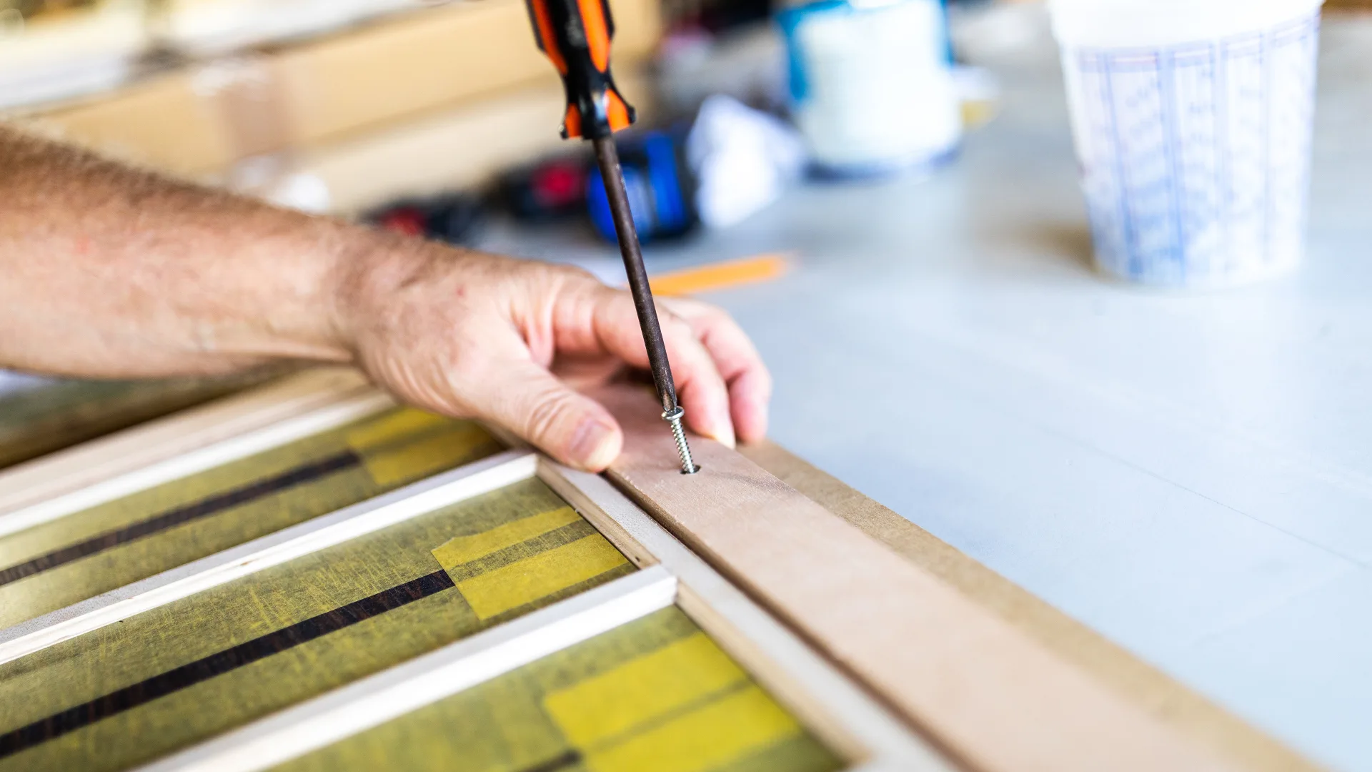 Technician measuring varnished wood trim on a bench in Stuart