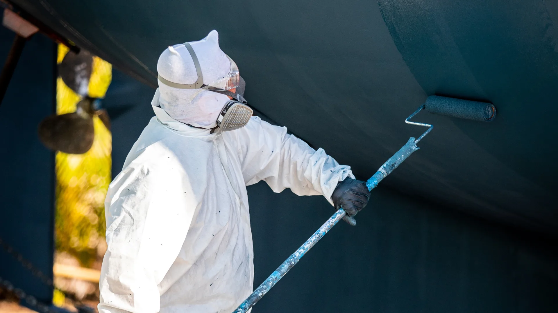 Technician applying bottom paint to a raised hull in Stuart