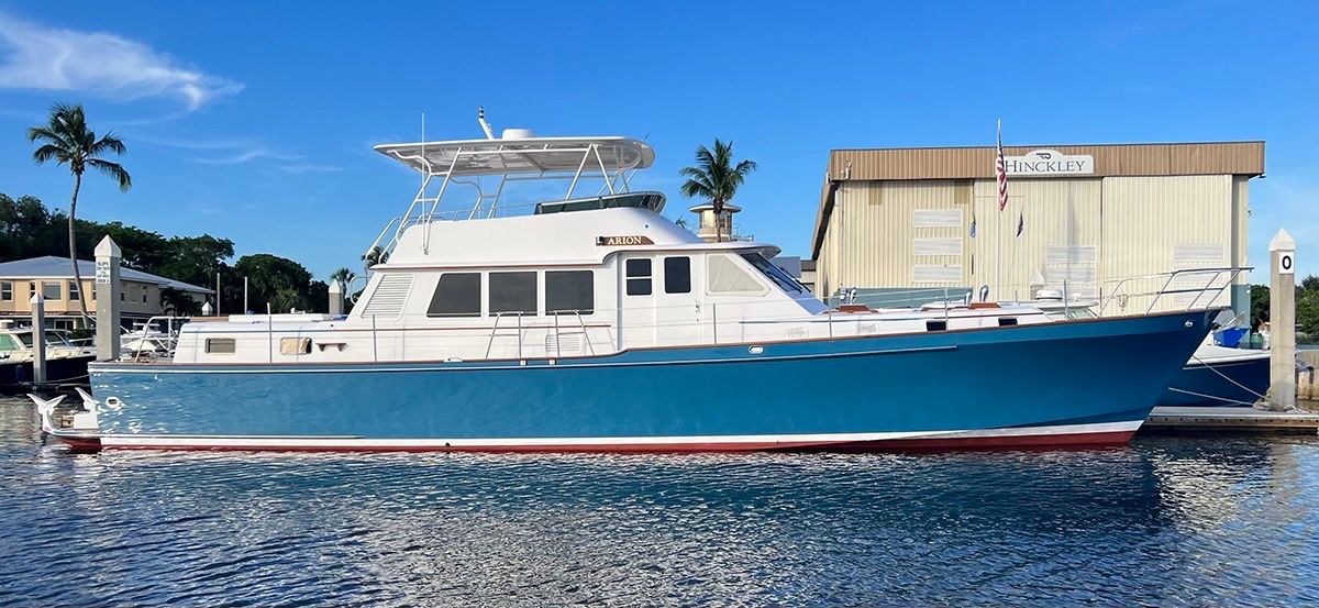Hinckley motor yacht docked at a marina, shown in profile with a blue hull and white cabin.
