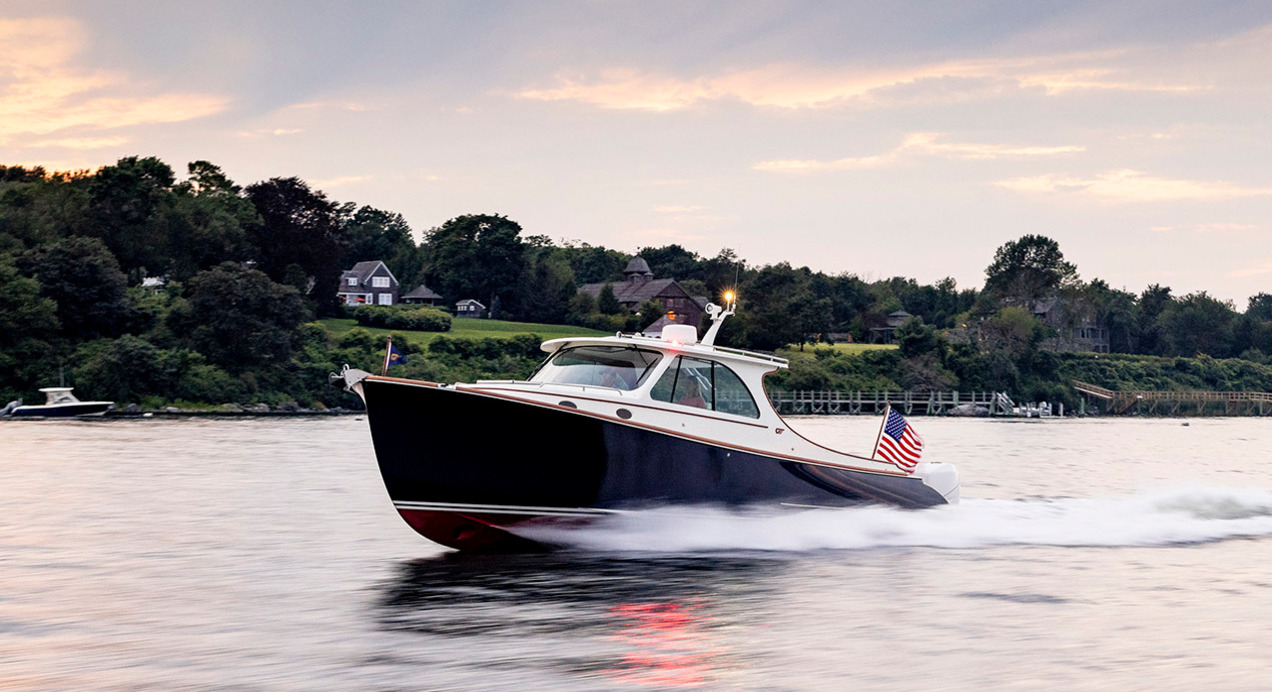 Hinckley motor yacht cruising at sunset along scenic coastline