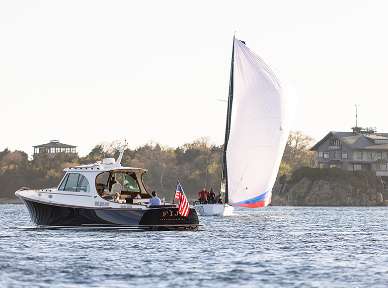 Hinckley yacht cruising on coastal waters alongside a sailboat during a regatta.
