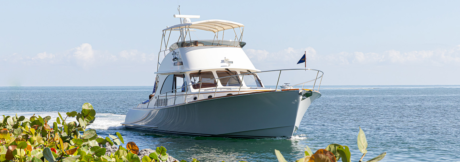 Hinckley Talaria yacht cruising along the coastline on calm ocean water