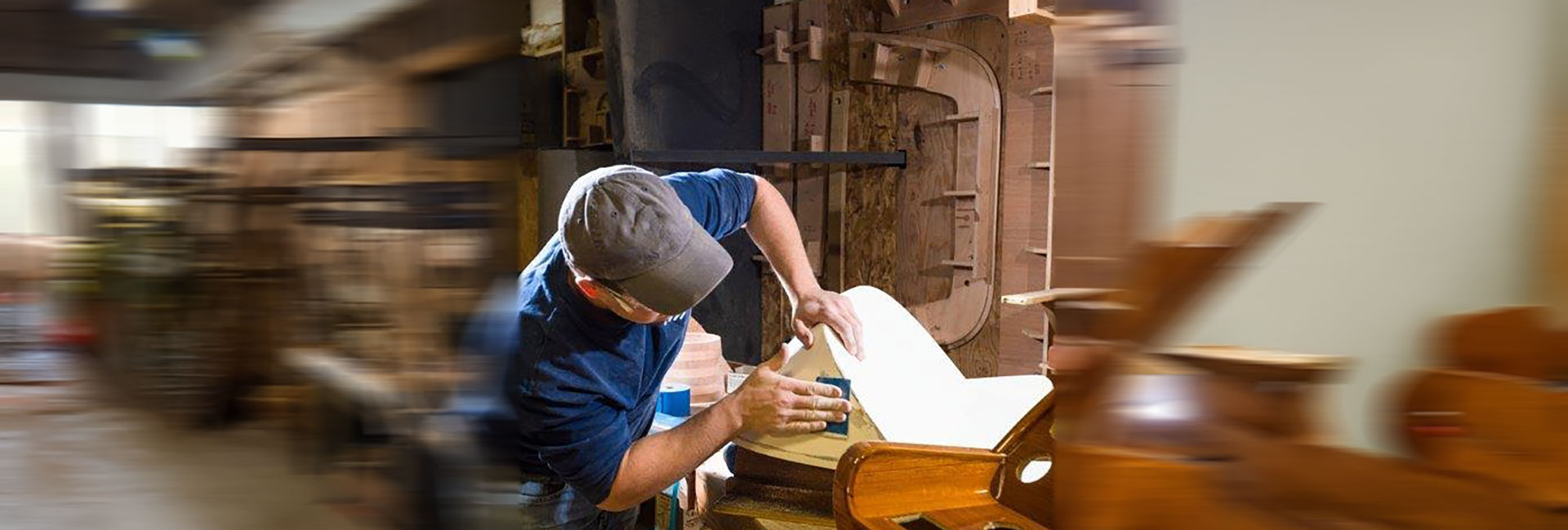 Hinckley Yachts craftsman hand-finishing wooden boat component at Topsham Maine facility