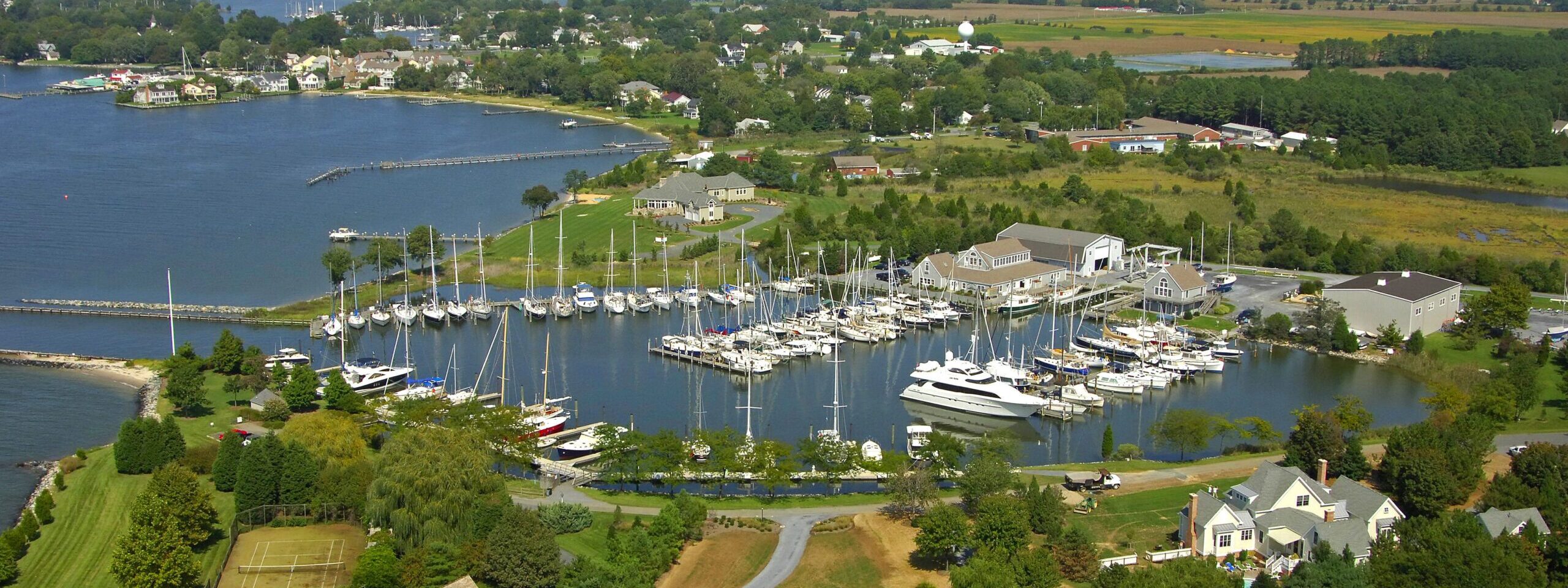 Aerial view of Hinckley Yacht Services’ Bachelor Point marina in Oxford, Maryland, with sailboats docked along the waterfront.