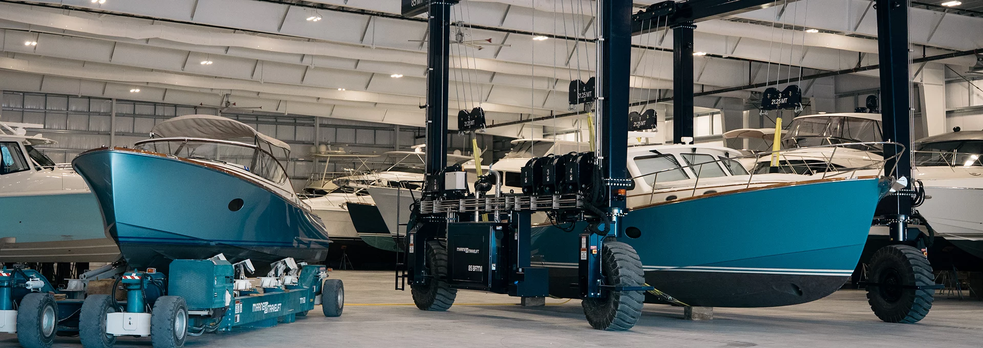 Hinckley boats stored indoors on heavy-duty lifts inside a climate-controlled yacht storage facility.