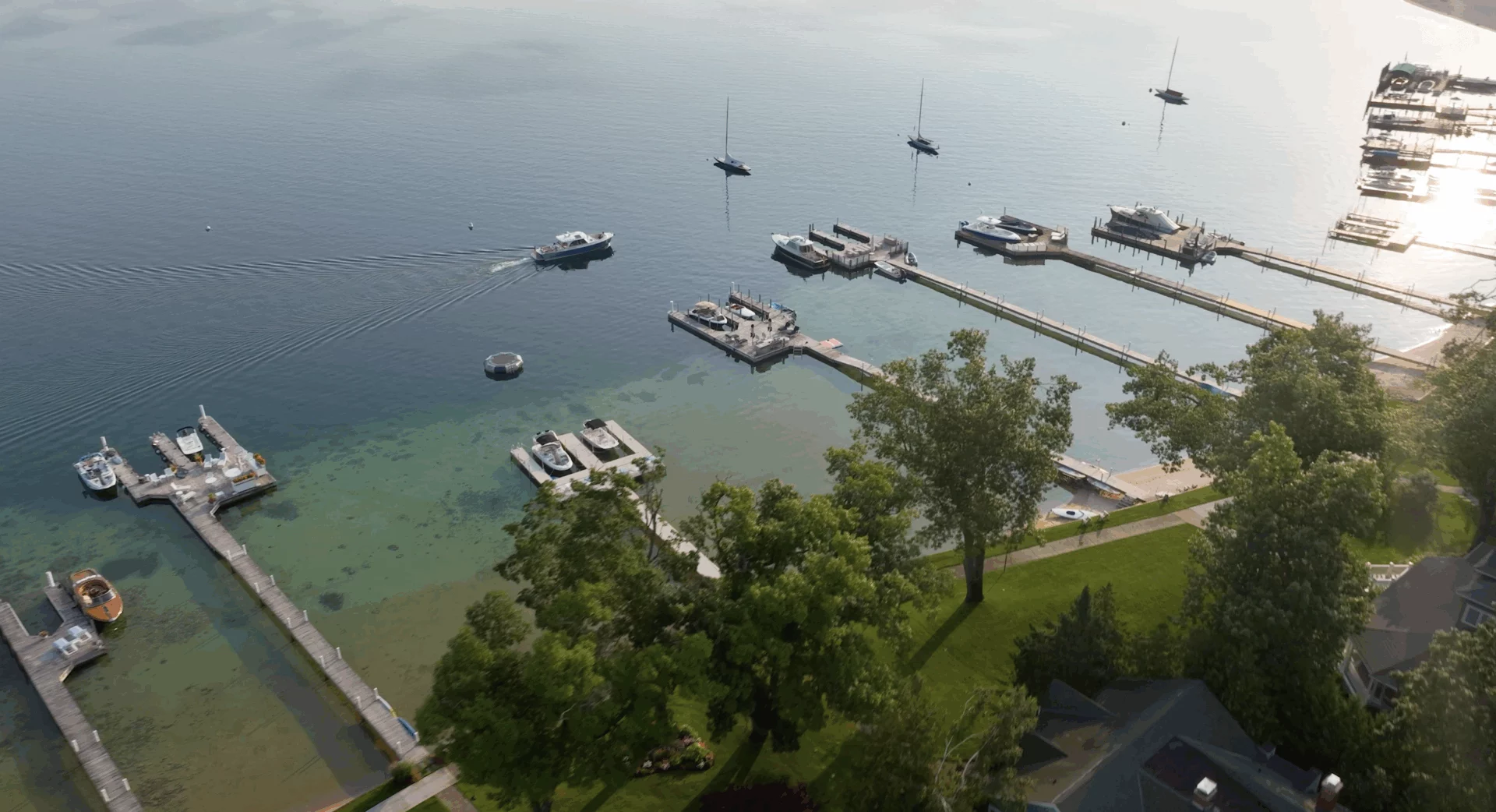 Aerial view of a marina with docks and boats on calm water, seen from above on a clear day.