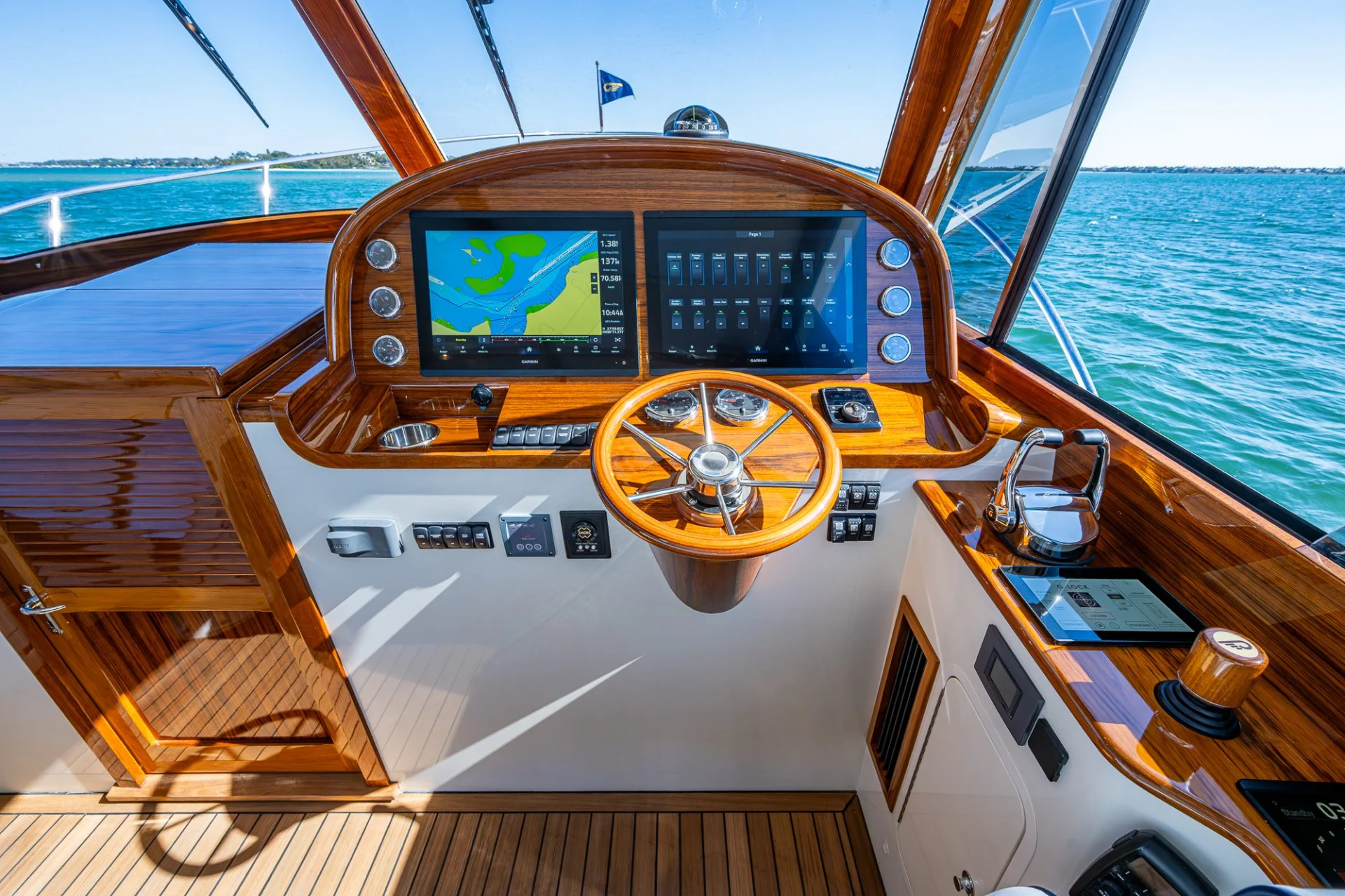 Hinckley yacht helm station with dual navigation displays, integrated marine electronics and teak dashboard at sea