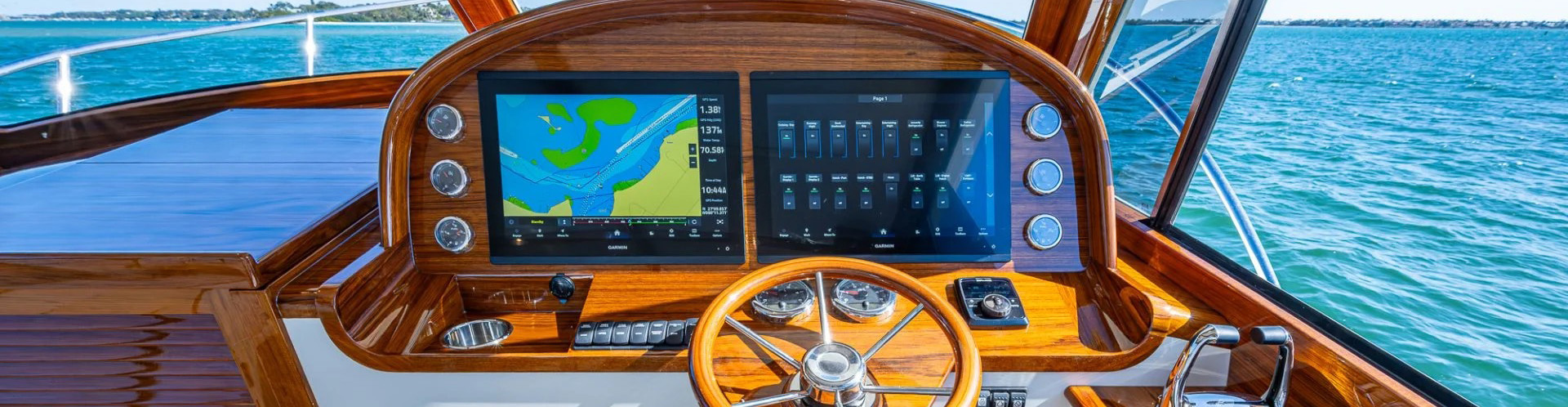 Hinckley yacht helm station with dual navigation displays, integrated marine electronics and teak dashboard at sea