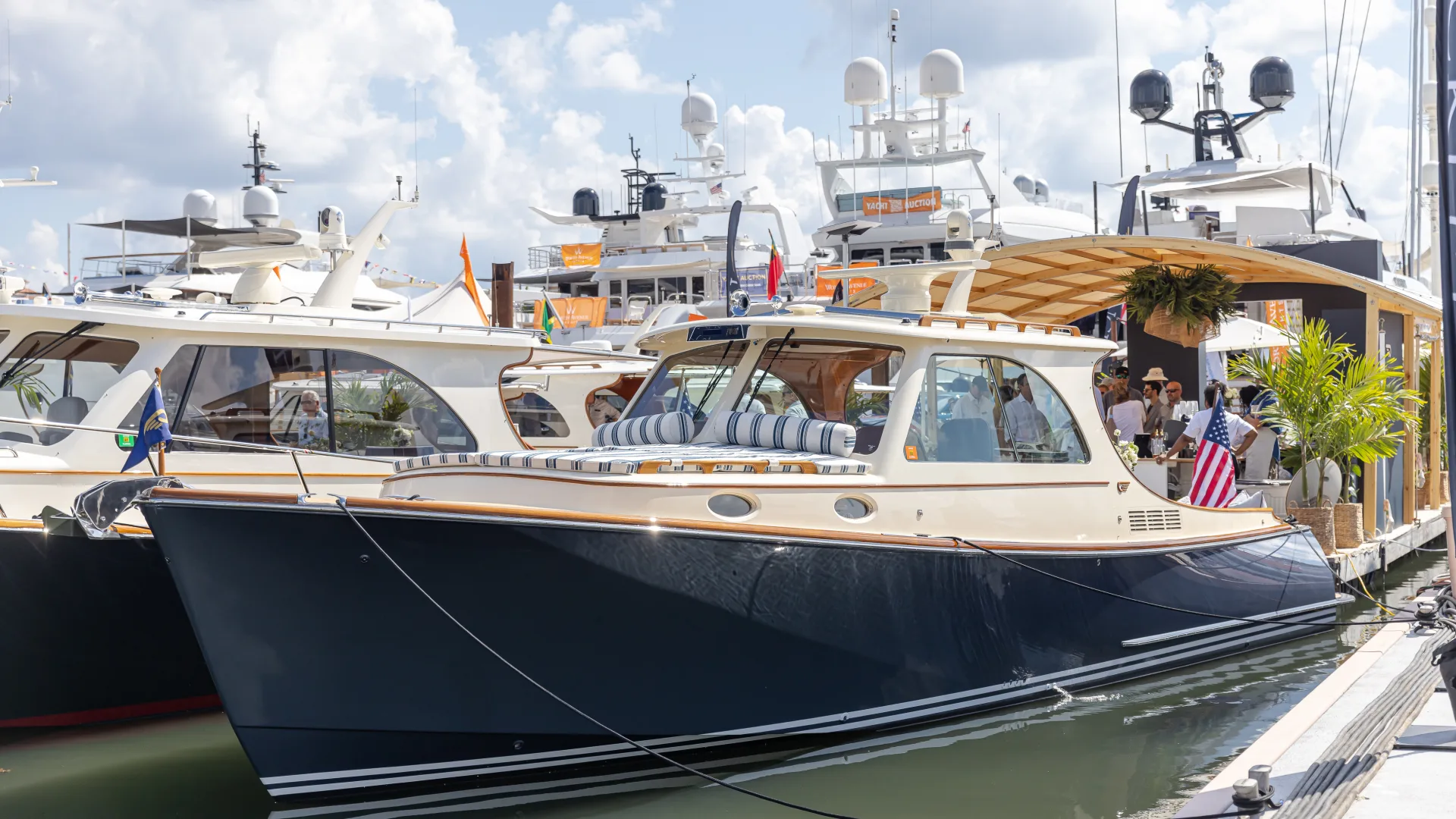 Hinckley Picnic Boat docked at marina during boat show with luxury yachts in background