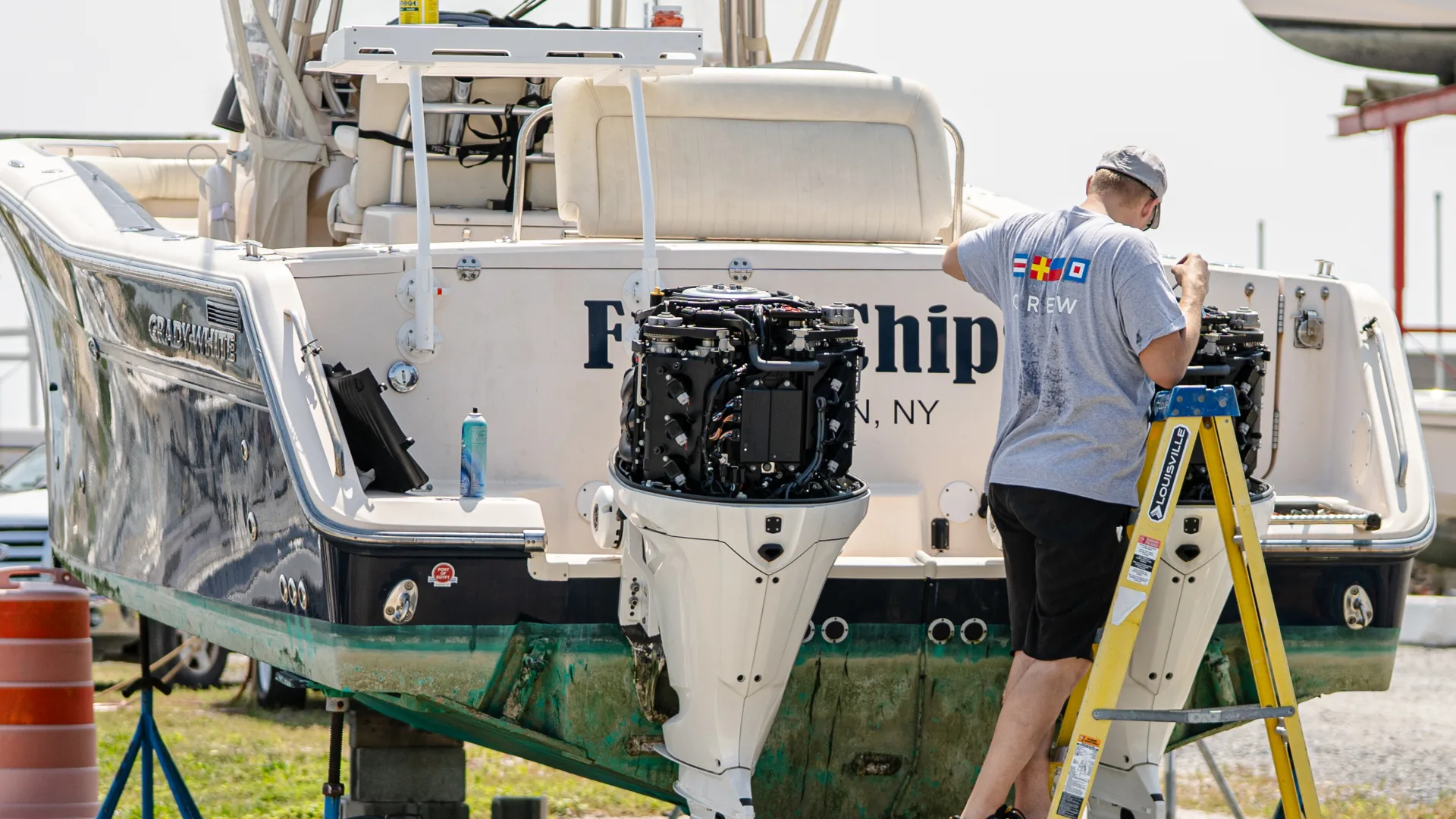 Technician aligning equipment behind a white boat in Southold
