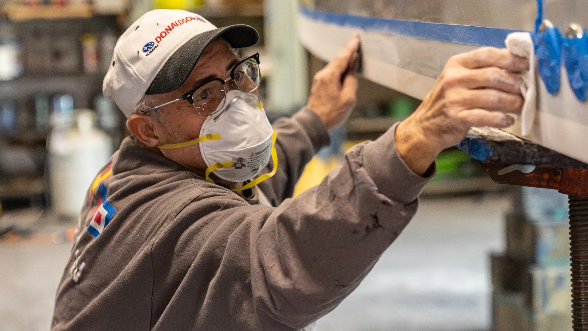 Technician sanding the side of a white hull in Southold