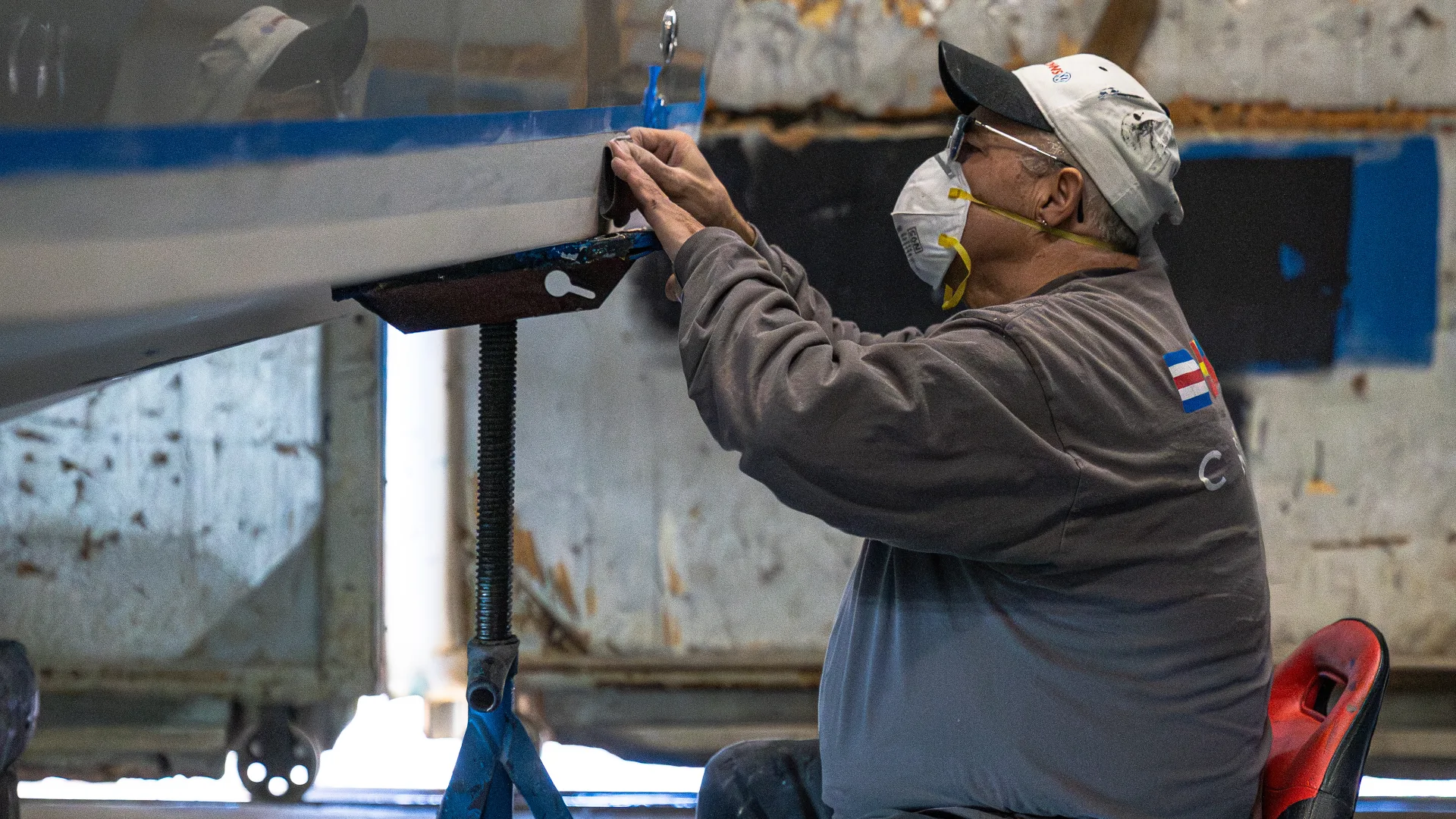 Technician sanding the underside of a raised hull in Southold