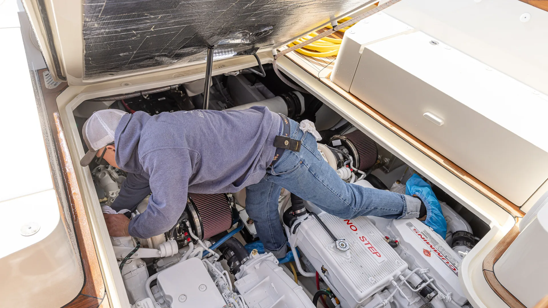 Technician working inside an open engine compartment in Stevensville
