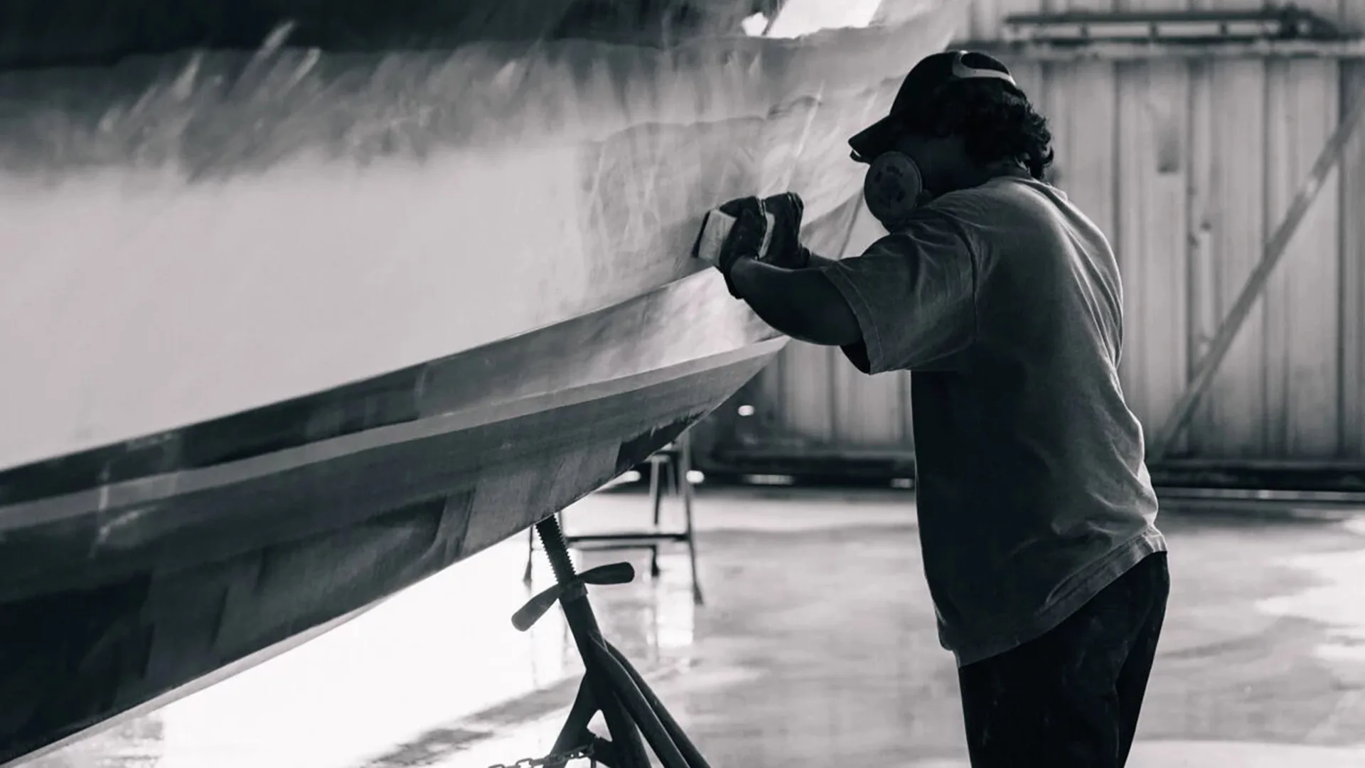 Technician sanding the side of a white hull in Stevensville