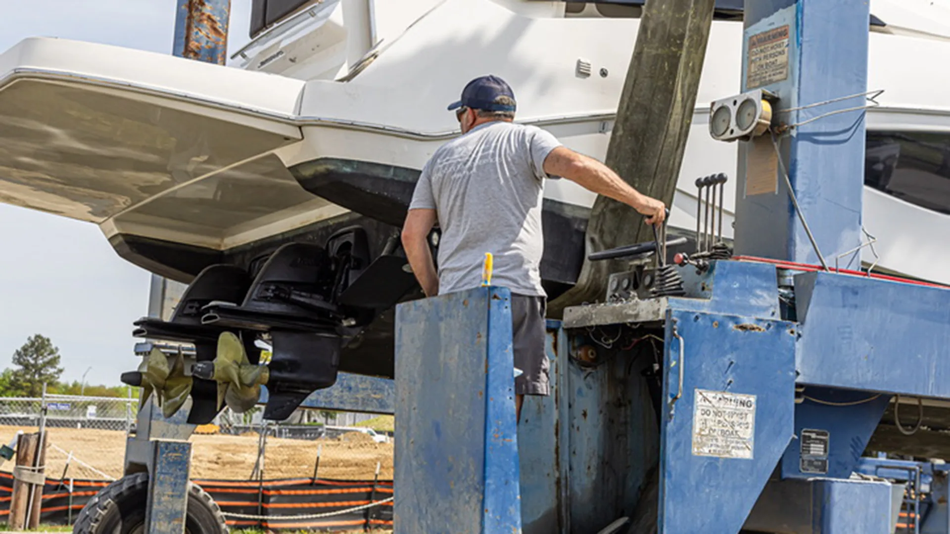 Technician guiding a boat while it is held on a lift in Stevensville
