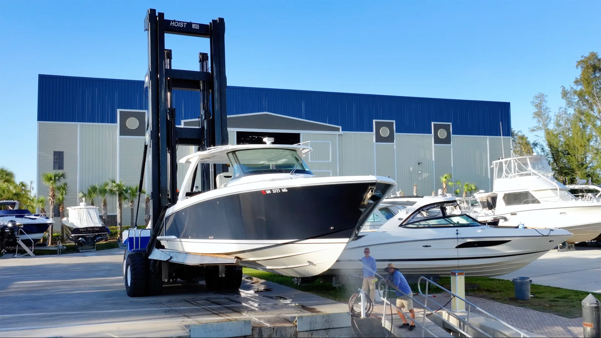 Forklift carrying a white powerboat across the Fort Myers service yard