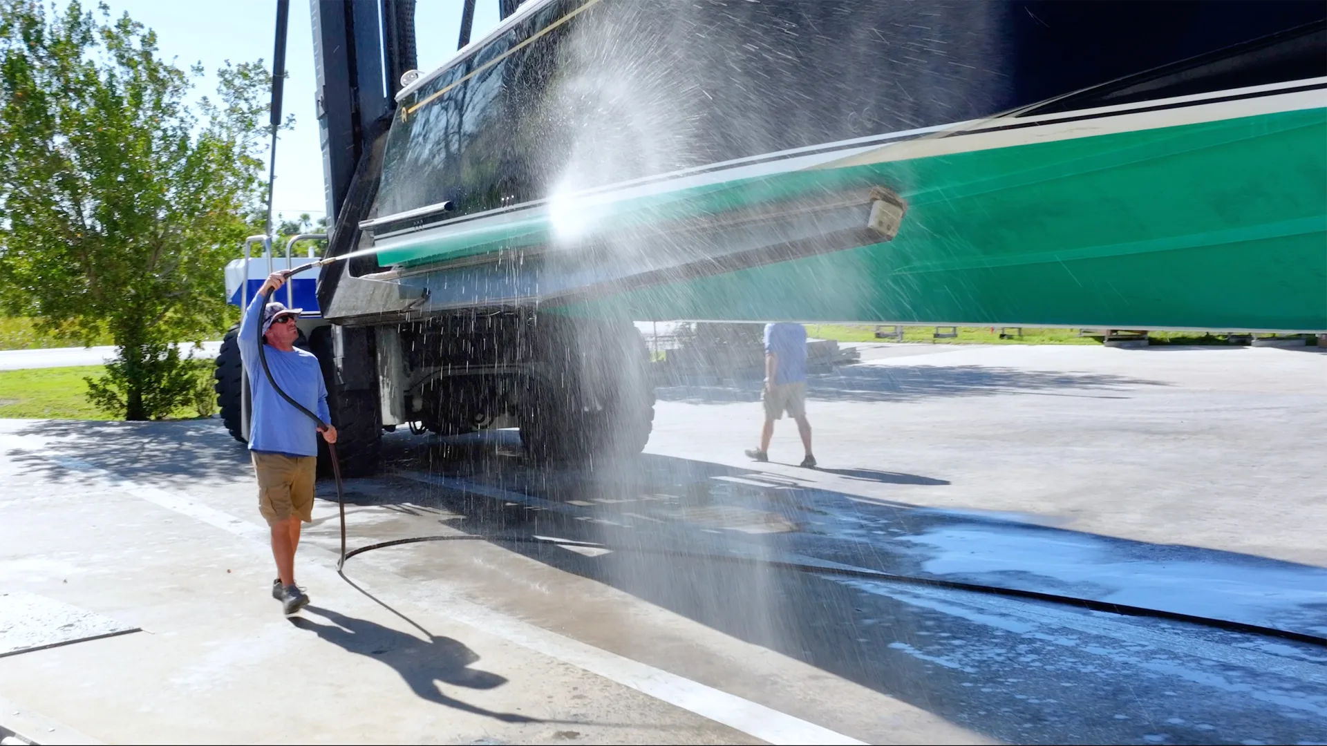 Technician pressure washing the side of a boat hull at Fort Myers